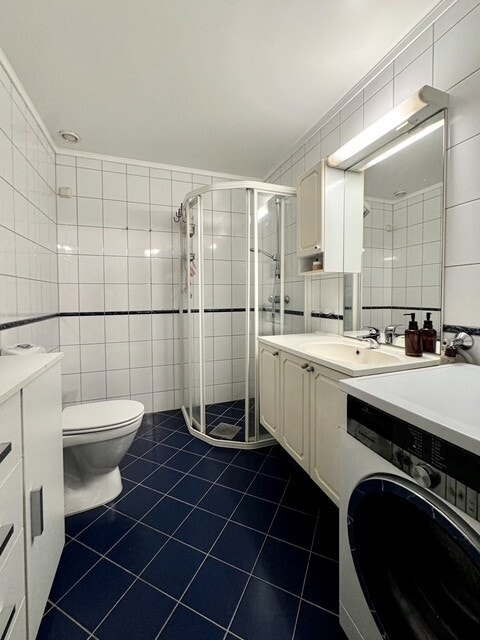 Flislagt bad utstyrt med vaskemaskin. Galleribilde