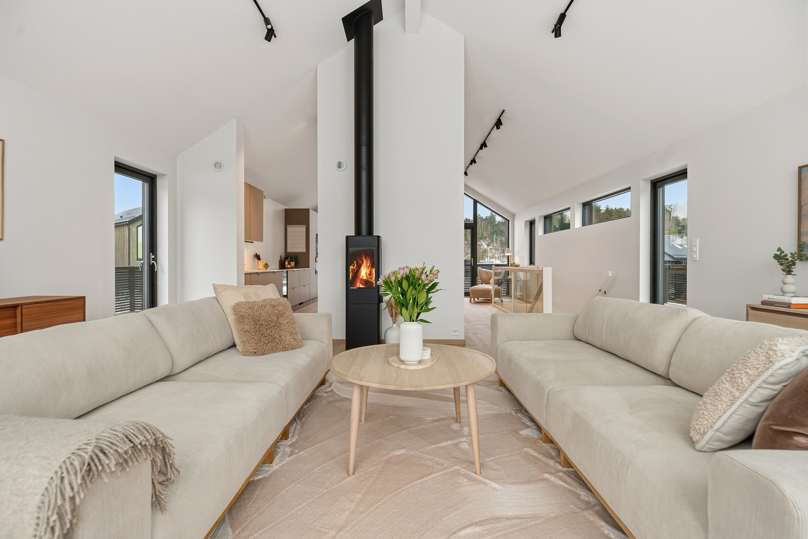 En sentralt plassert peisovn gir fine, definerte soner for møblering i allrommet som utgjør stue og kjøkken. Galleribilde