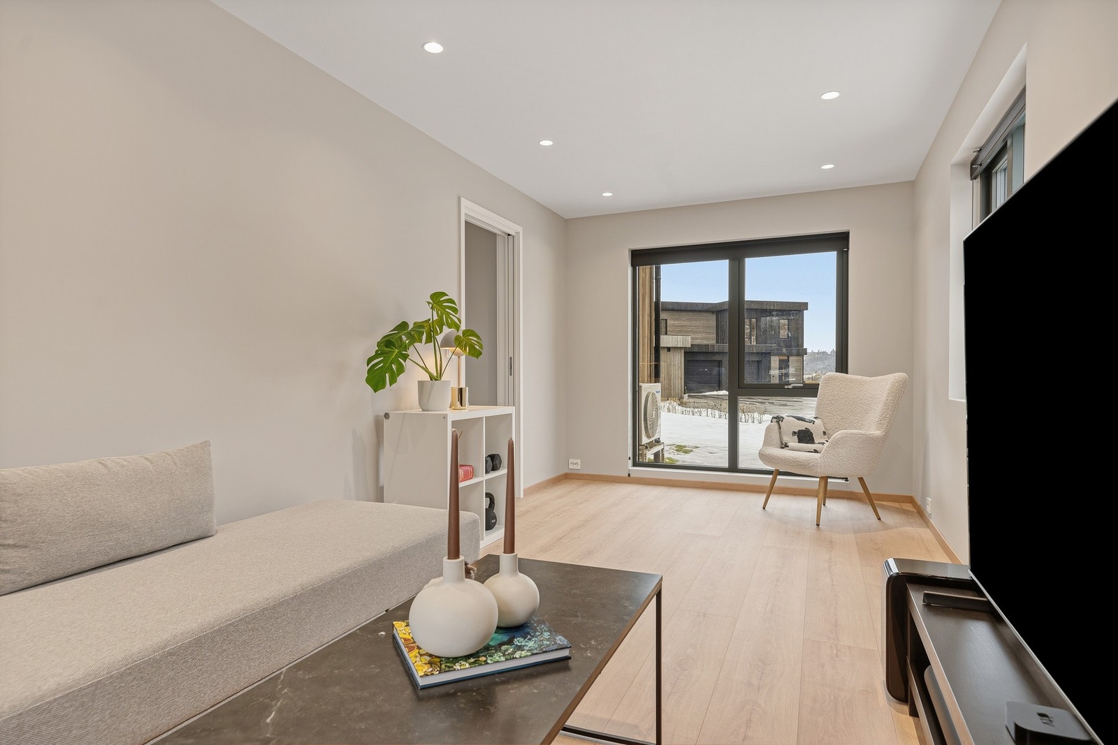 Tv-stuen har gråmalte, glatte vegger, downlights i himlingen og lys, enstavs gulv. Galleribilde