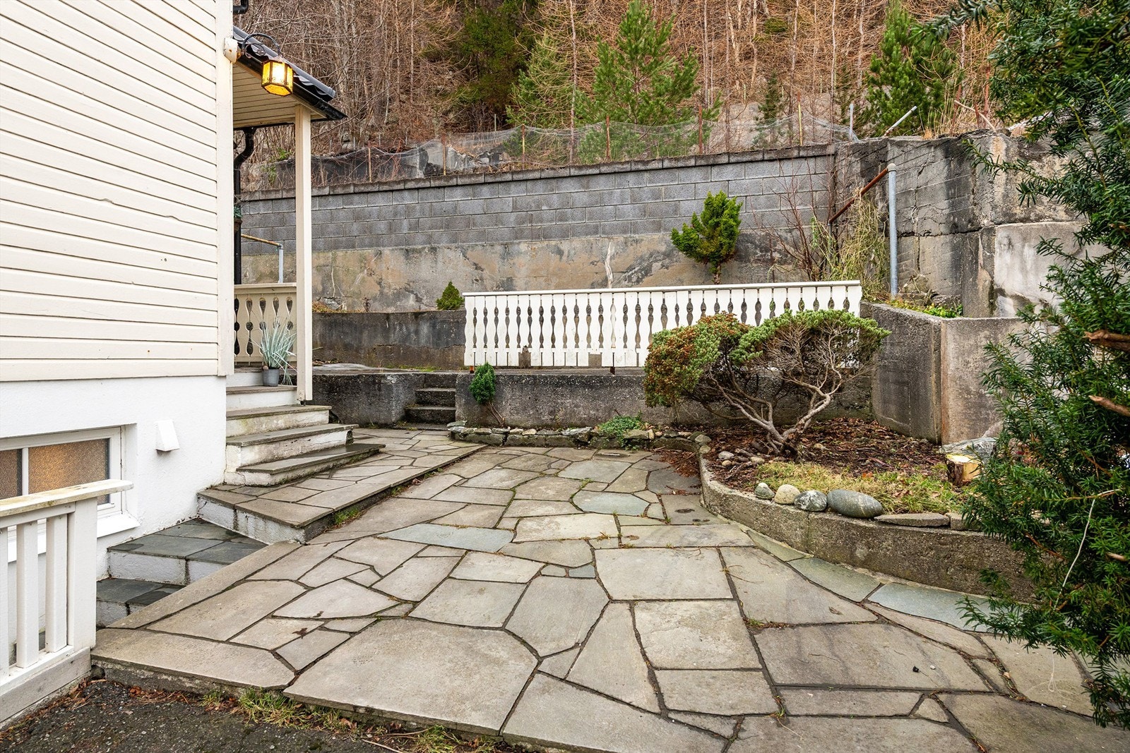 Hellebelagt inngangsparti med beplantning og felles uteplass mot syd. Galleribilde