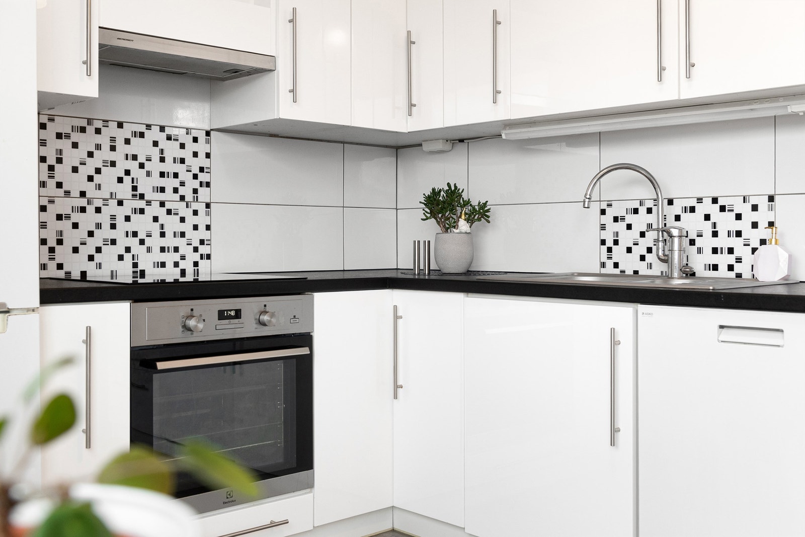 Detaljefoto fra kjøkken - Det er lagt fliser mellom kjøkkenbenk og overskap Galleribilde