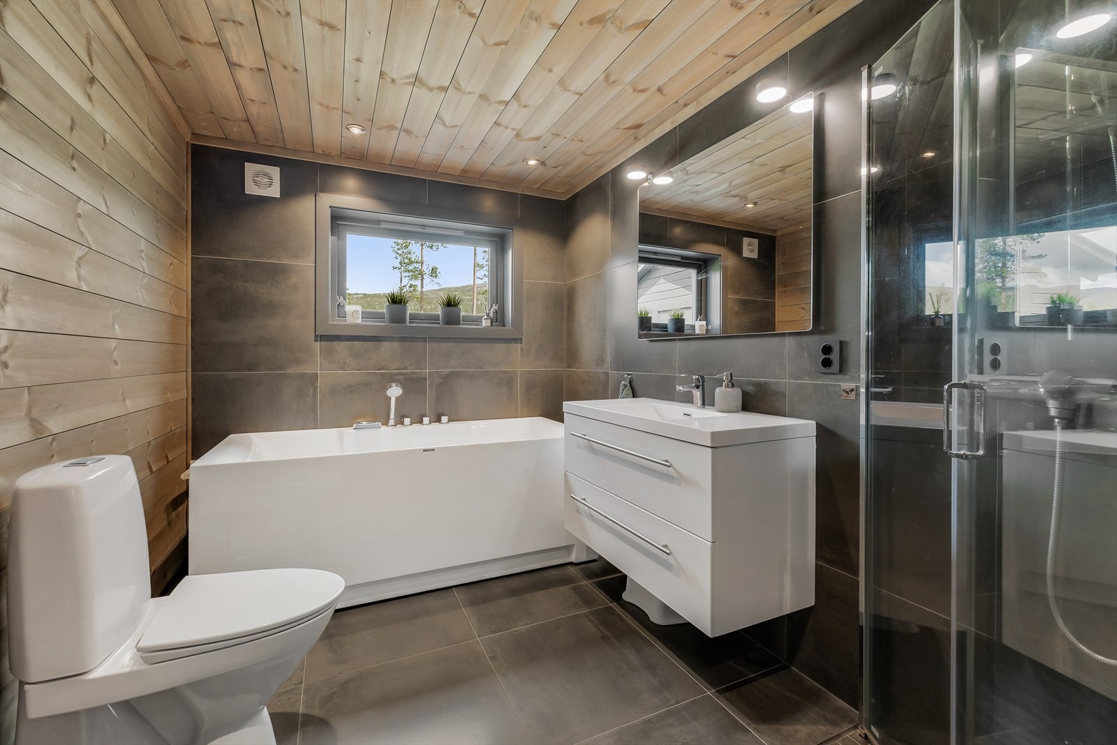 Pent bad med flis på gulv og flis/trepanel på vegg som gir et moderne uttrykk Galleribilde