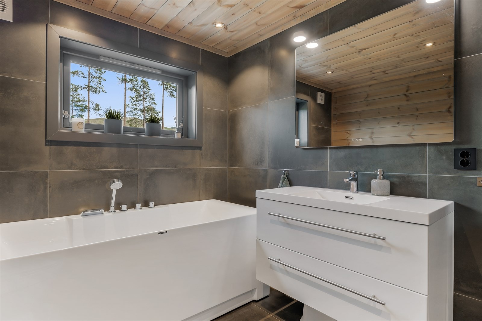 Badet har moderene innredning og er utstyrt med badekar Galleribilde