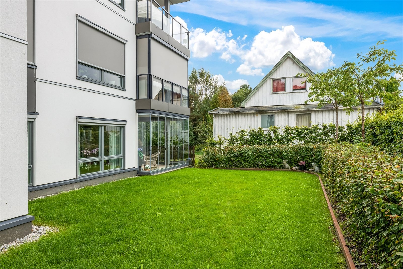 Utenfor leiligheten er det gressplen og busker. Galleribilde