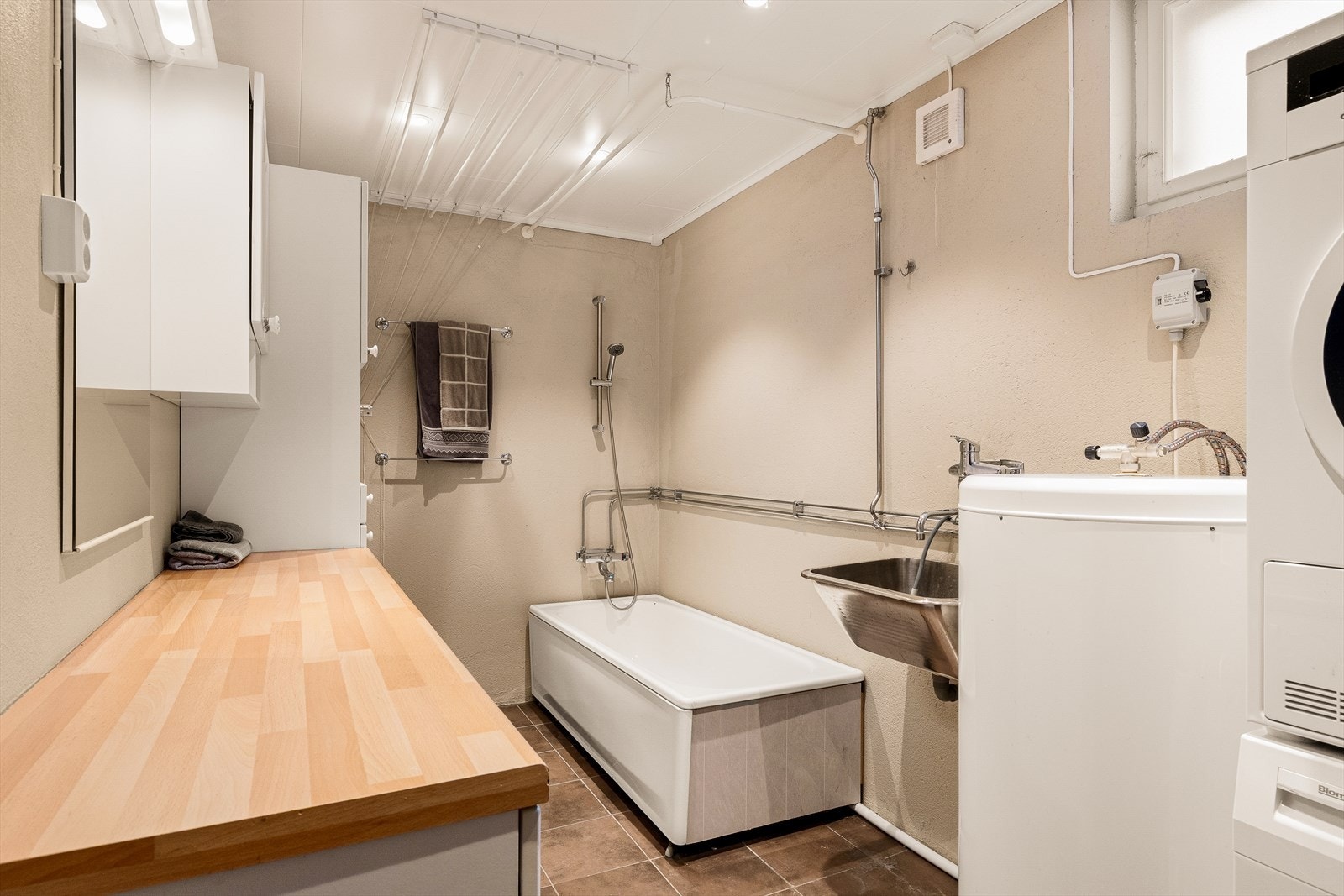 Vaskerom/bad. Rommet er innredet med badekar, skyllekum, benk, speil, skap og opplegg for vaskemaskin. Galleribilde