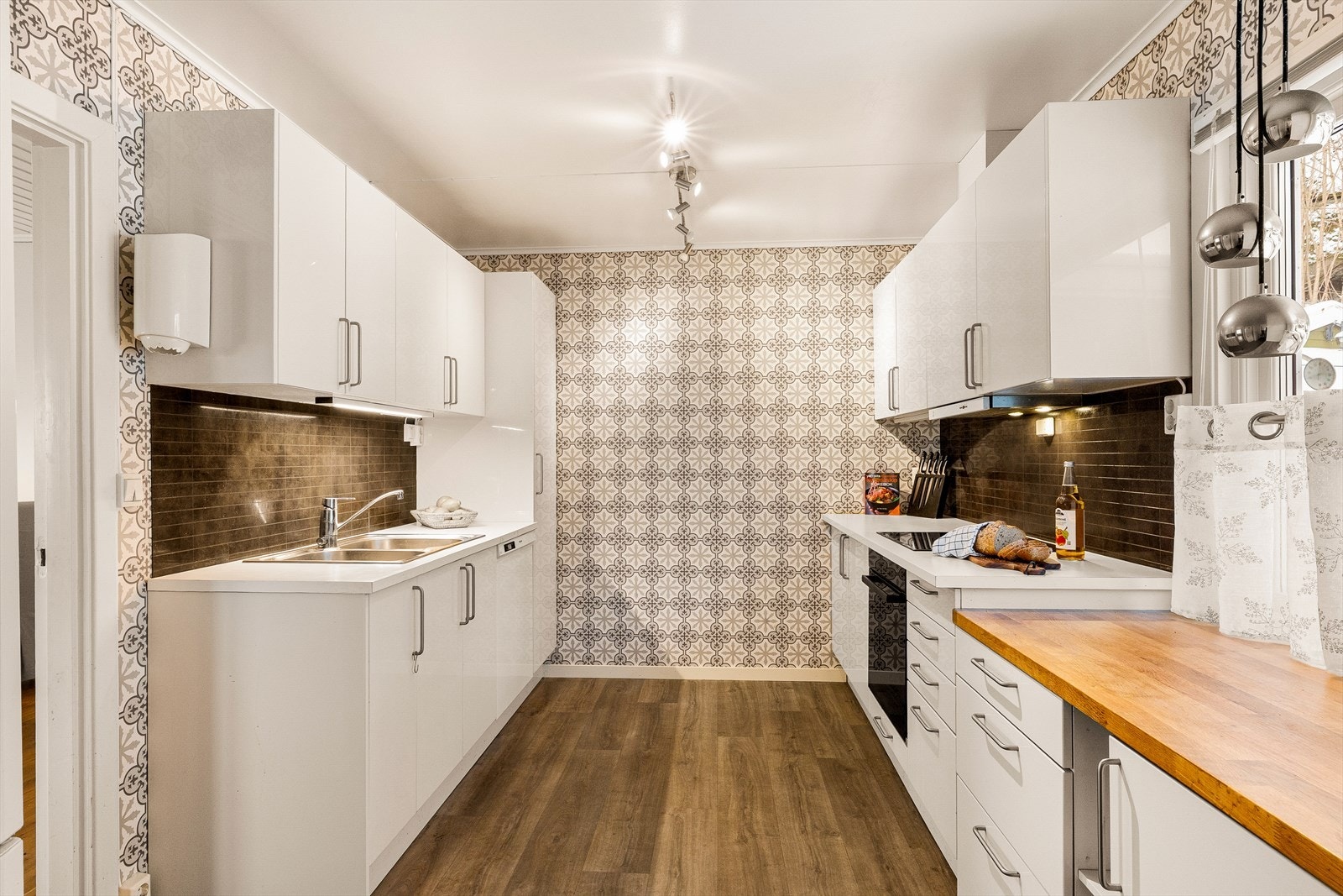 Lyst kjøkken med glatte fronter og benkeplate av heltre og laminat. Galleribilde