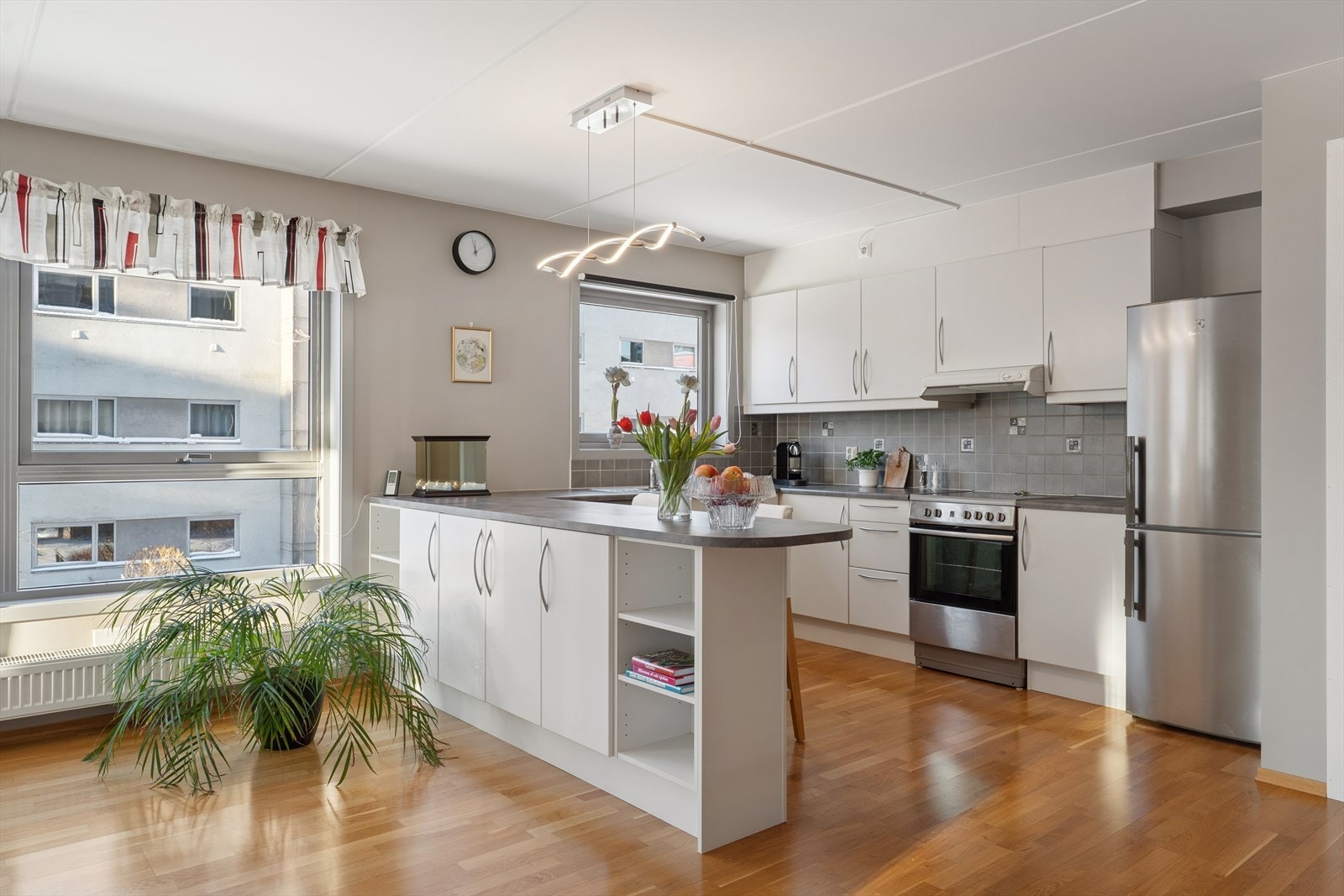 Lyst og tidløst kjøkken med hvite slette fronter og benkeplate av typen laminat. Galleribilde