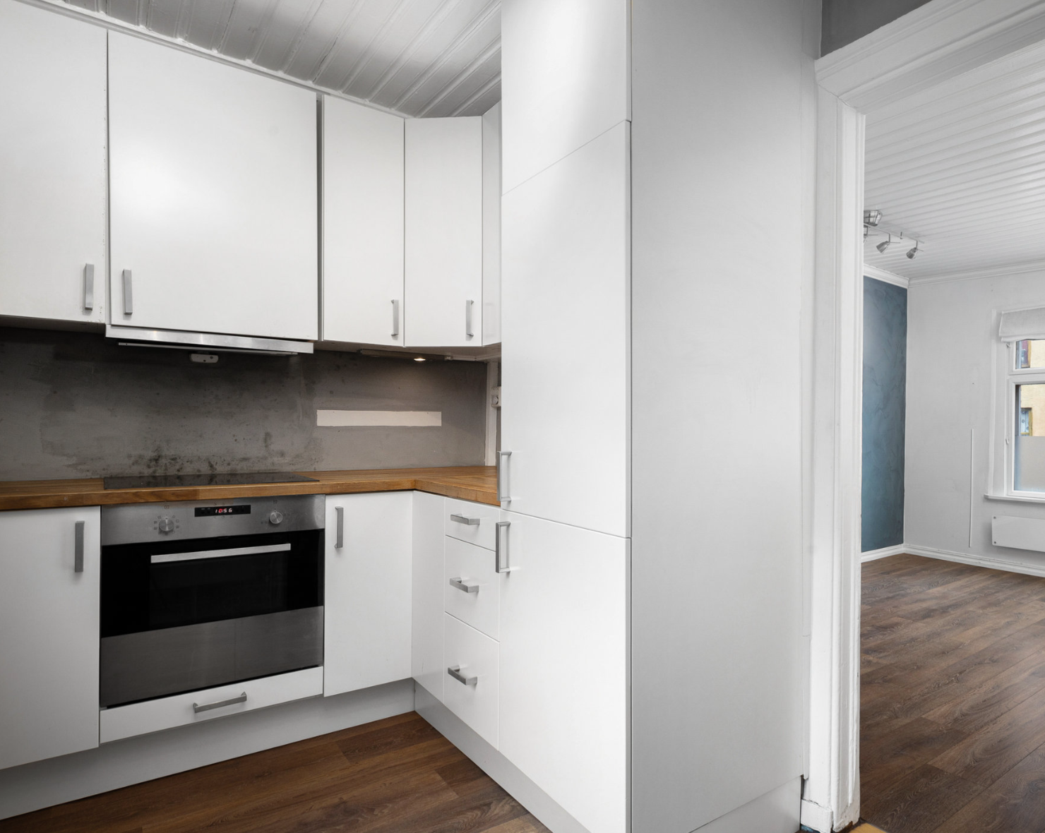 IKEA kjøkken med glatte, hvite fronter og heltre benkeplate med nedfelt stålkum. Integrerte hvitevarer som induksjonstopp, stekeovn, oppvaskmaskin og kjøl/frys. Ventilator over koketoppen. Kjøkkeninnredningen har fått TG3 og bør oppgraderes. Galleribilde