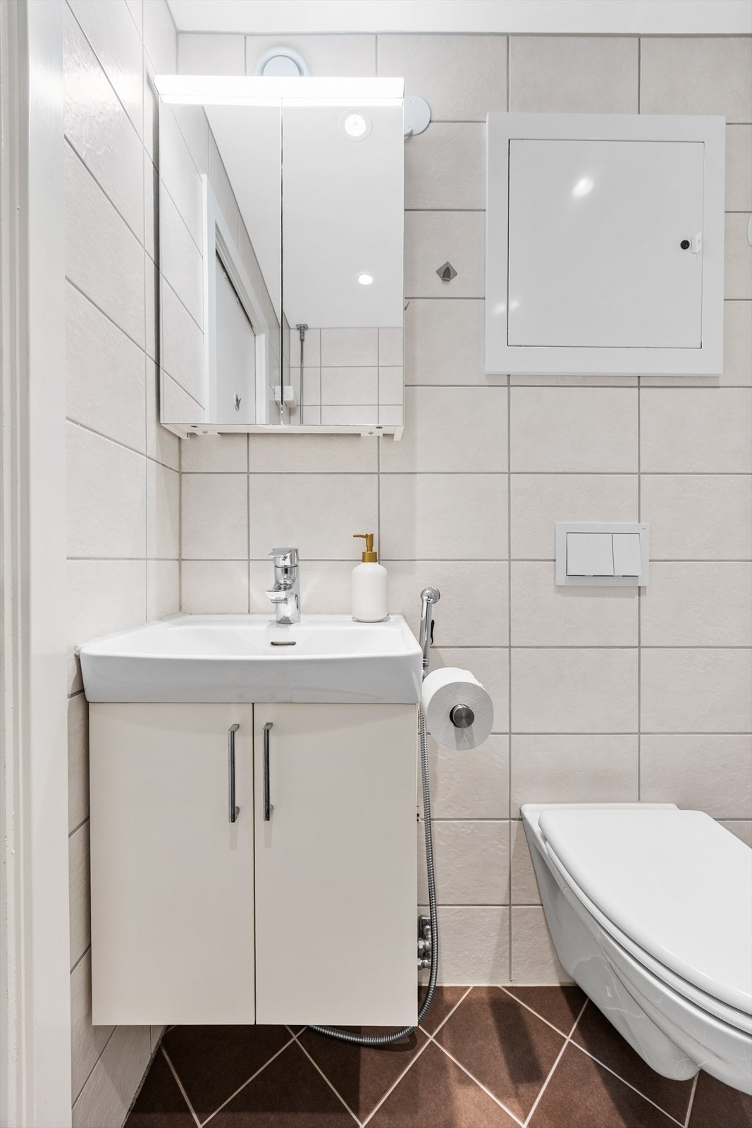 Baderomsinnredningen består av servant, overskap med speil og lys, vegghengt toalett og dusjhjørne med innfellbare glassdører. Galleribilde