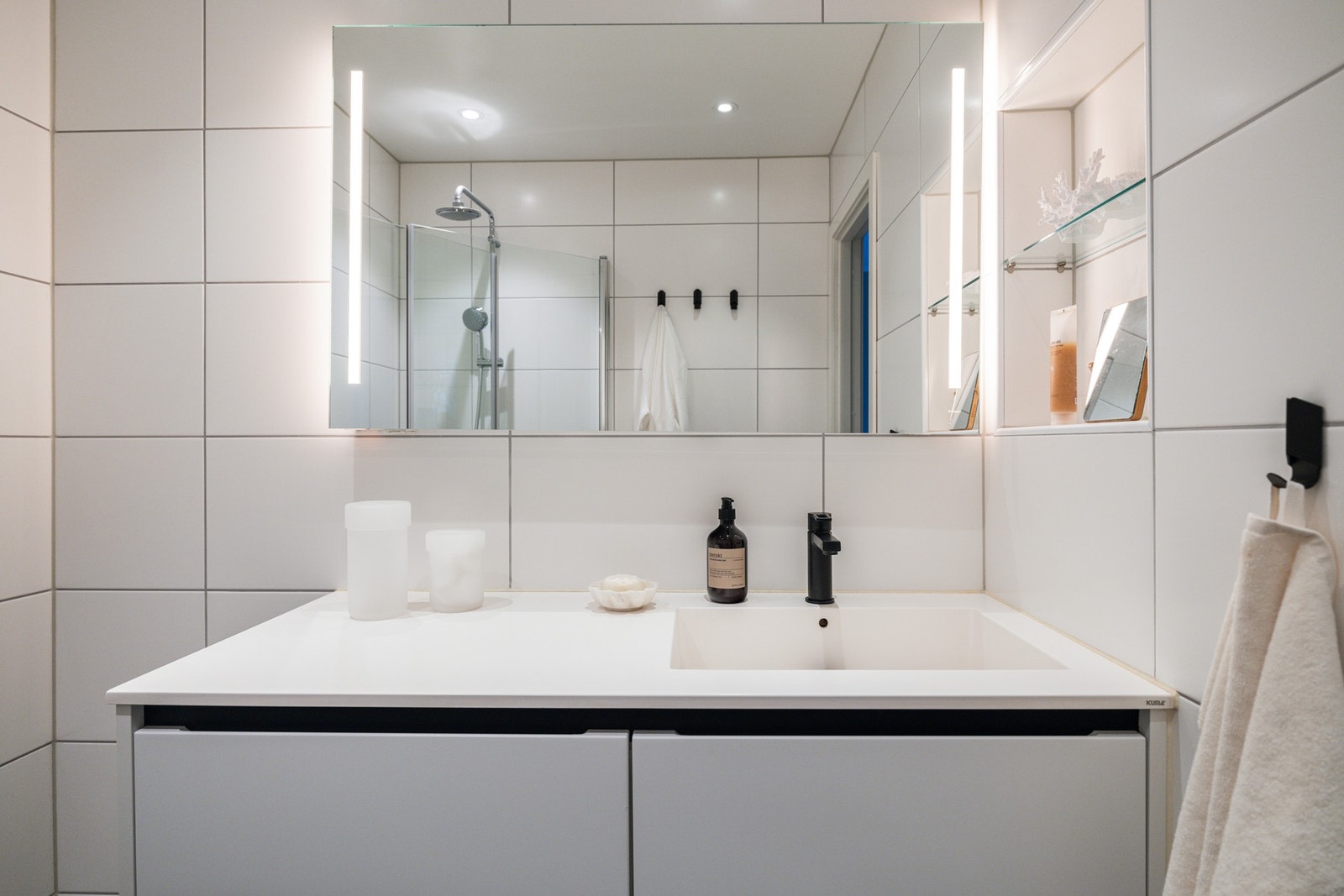 Stor baderomsinnredning med heldekkende servant med Tapwell mattsvart kran og skuffeseksjon under med sorte detaljer som gir et stilrent uttrykk Galleribilde