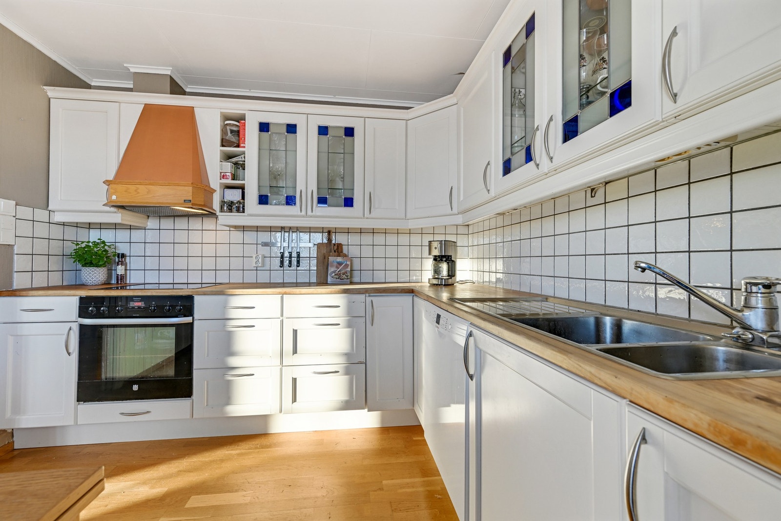 Kjøkkenet er lyst og har hvite og profilerte fronter. Det er godt med skap og skuffer for oppbevaring, samt en solid benkeflate Galleribilde