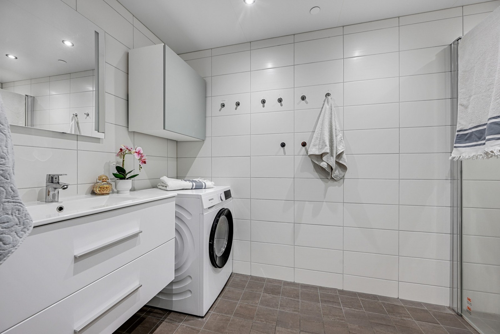 Flislagt bad med varmekabler, dusjhjørne, vegghngt toalett og opplegg til vaskemaskin Galleribilde