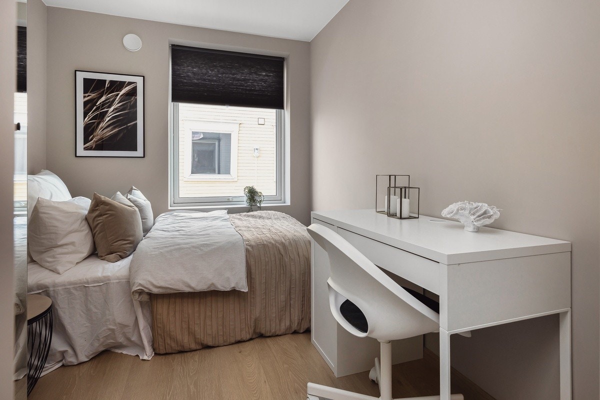 Råstilige soverom som er innredet med garderobeskap, seng, pult, stol, panelovn og plisségardin. Dette er Jupiter. Galleribilde