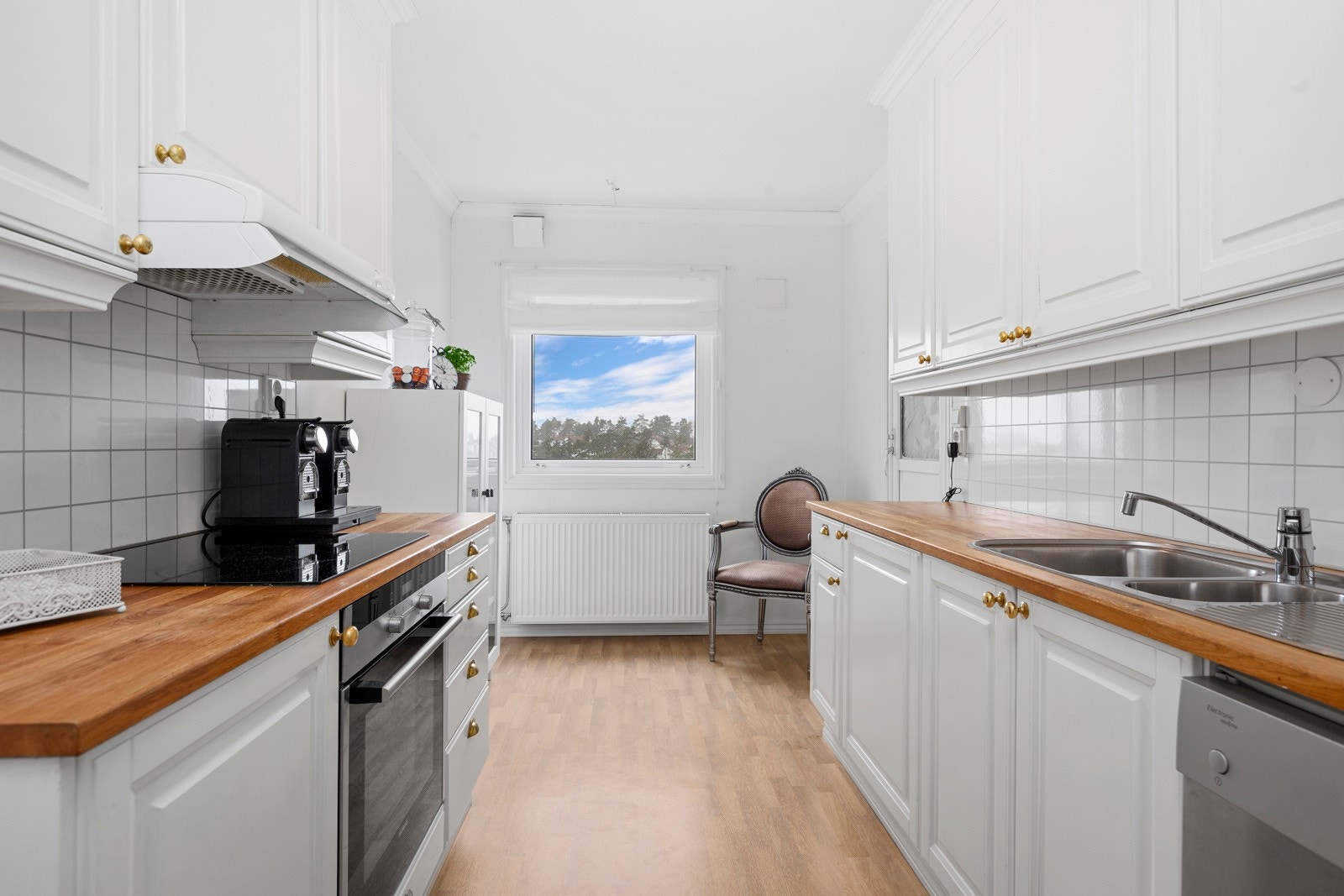 Kjøkkenet har en hvit profilert innredning med takhøye skap og godt med skapplass Galleribilde