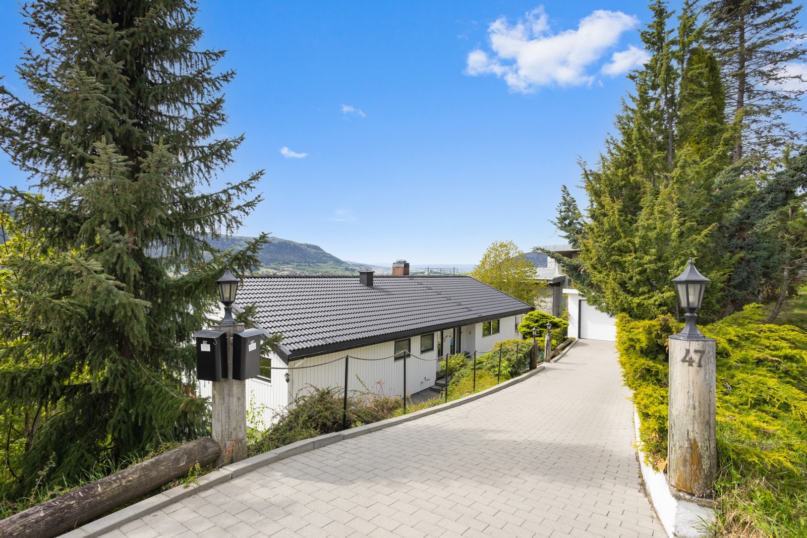 Ny steinbelagt gårdsplass som leder ned til dobbelgarasje Galleribilde