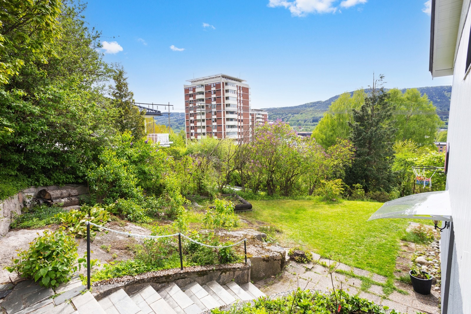 Steinsatt utvendig trapp ned fra gårdsplass til egen inngangsdør til sokkelleilighet fra siden av boligen Galleribilde