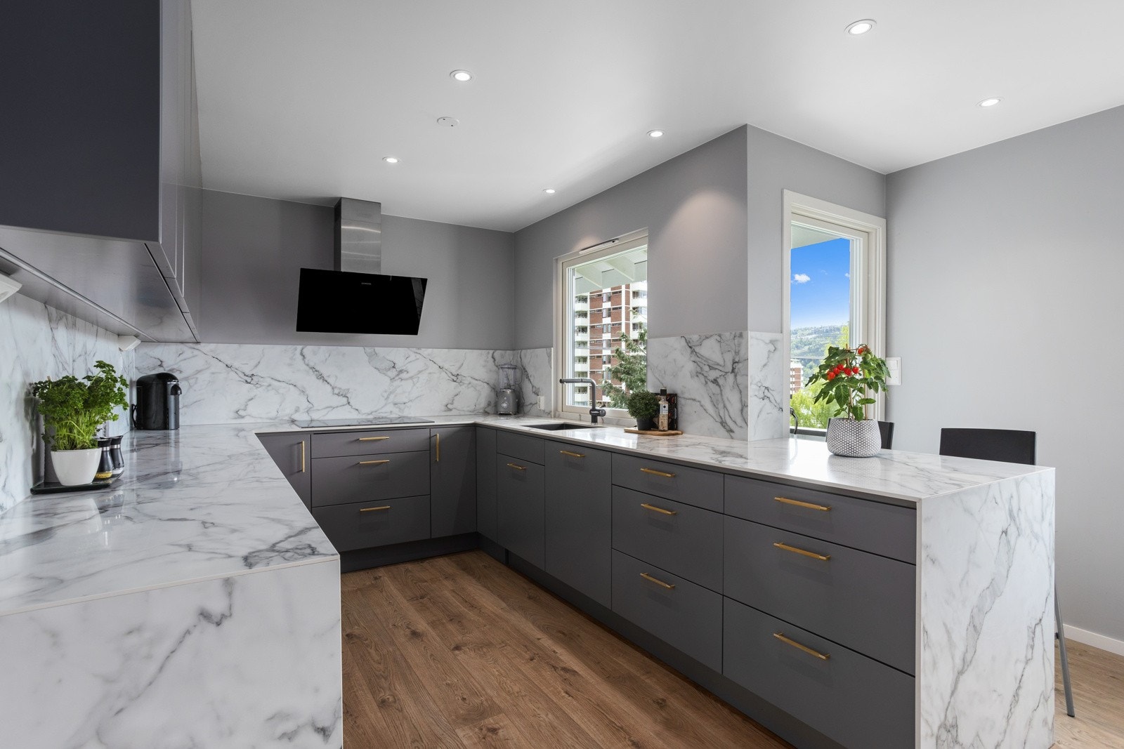 Benkeplate i kompositt i marmorimitasjon er trukket opp langs vegg mellom over- og underskap, samt ned til gulvet. En flott detalj. Galleribilde