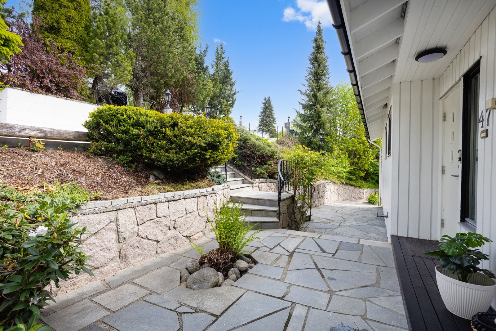 Representativt inngangsparti med steinheller og beplantning Galleribilde