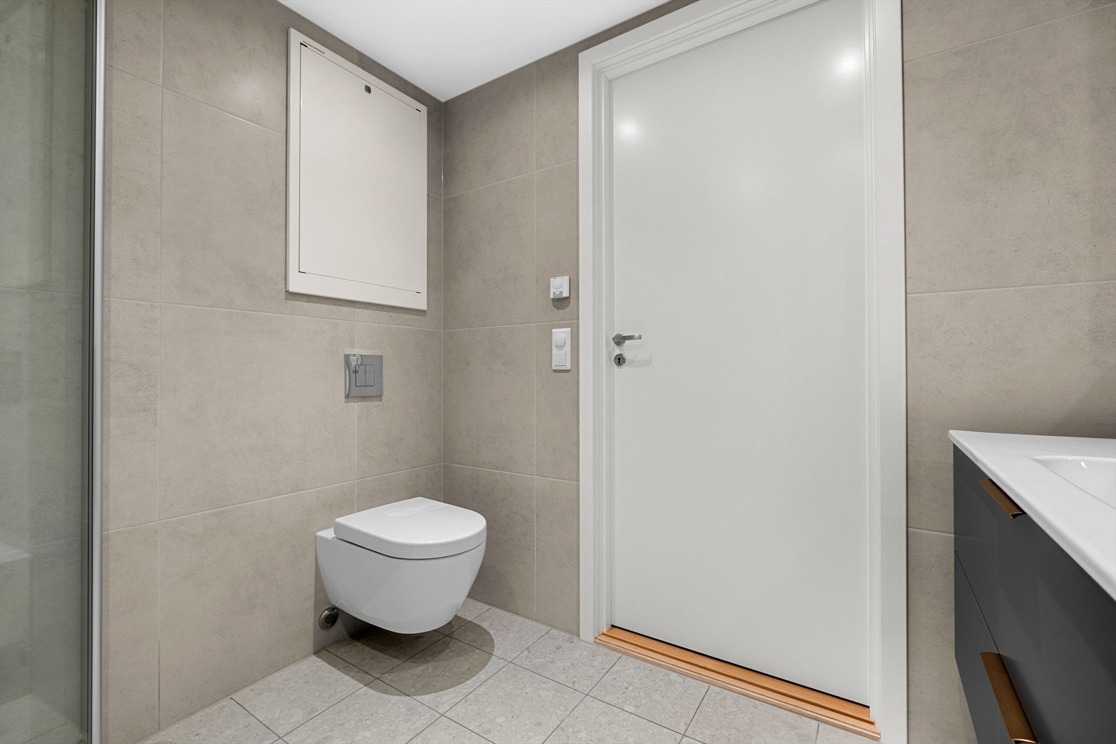 Badet er utstyrt med innfellbare dusjdører, vegghengt toalett, servantskap og opplegg for vaskemaskin. Galleribilde