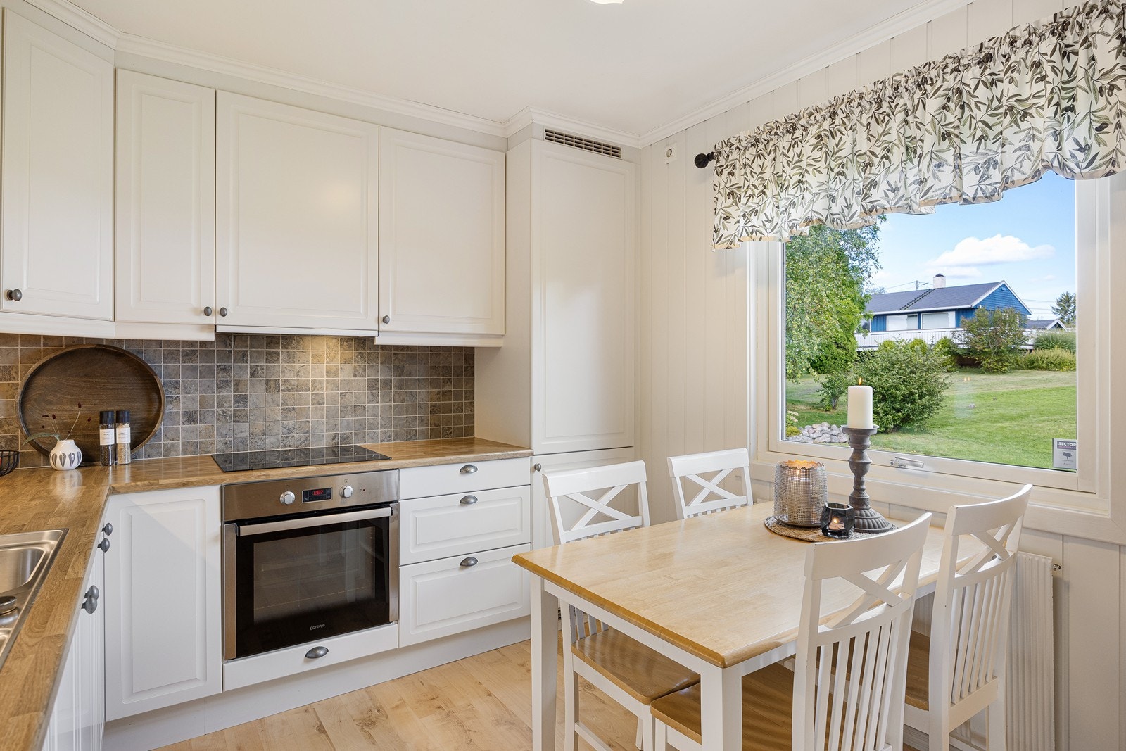 Innredningen har hvite, profilerte fronter og laminatbenkeplate med nedfelt, dobbel oppvaskkum. Galleribilde