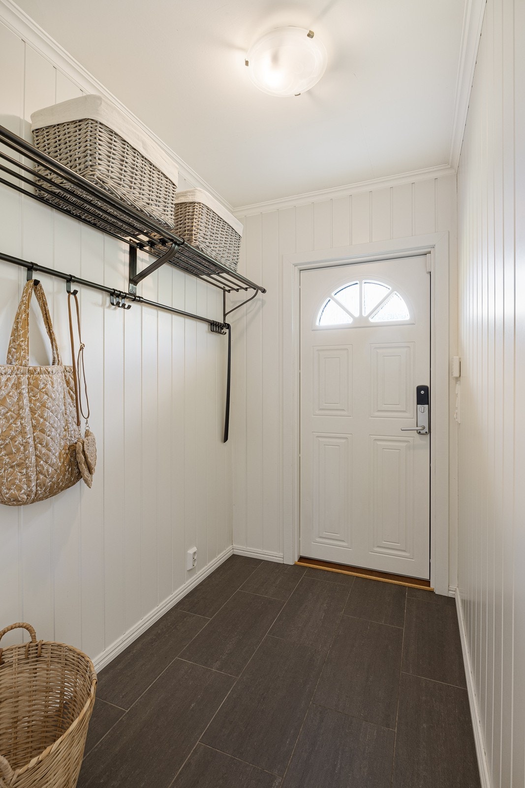 Entréen har lyse veggflater og mørke fliser på gulvet. Rommet har åpen garderobeløsning. Galleribilde