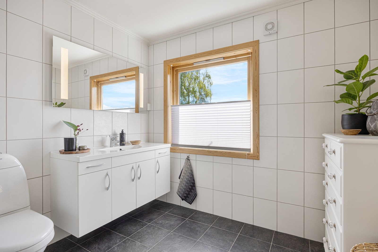 Badet er delikat og tidløst med sine flislagte overflater og lun gulvvarme. Galleribilde