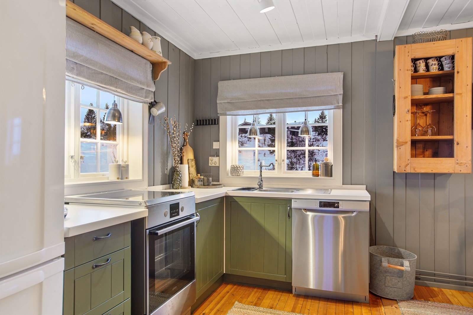 Kjøkkenet har en koselig og landlig stil, med innredning i malte folierte plater, benkeplate i trelaminat og stål oppvaskkum. Galleribilde