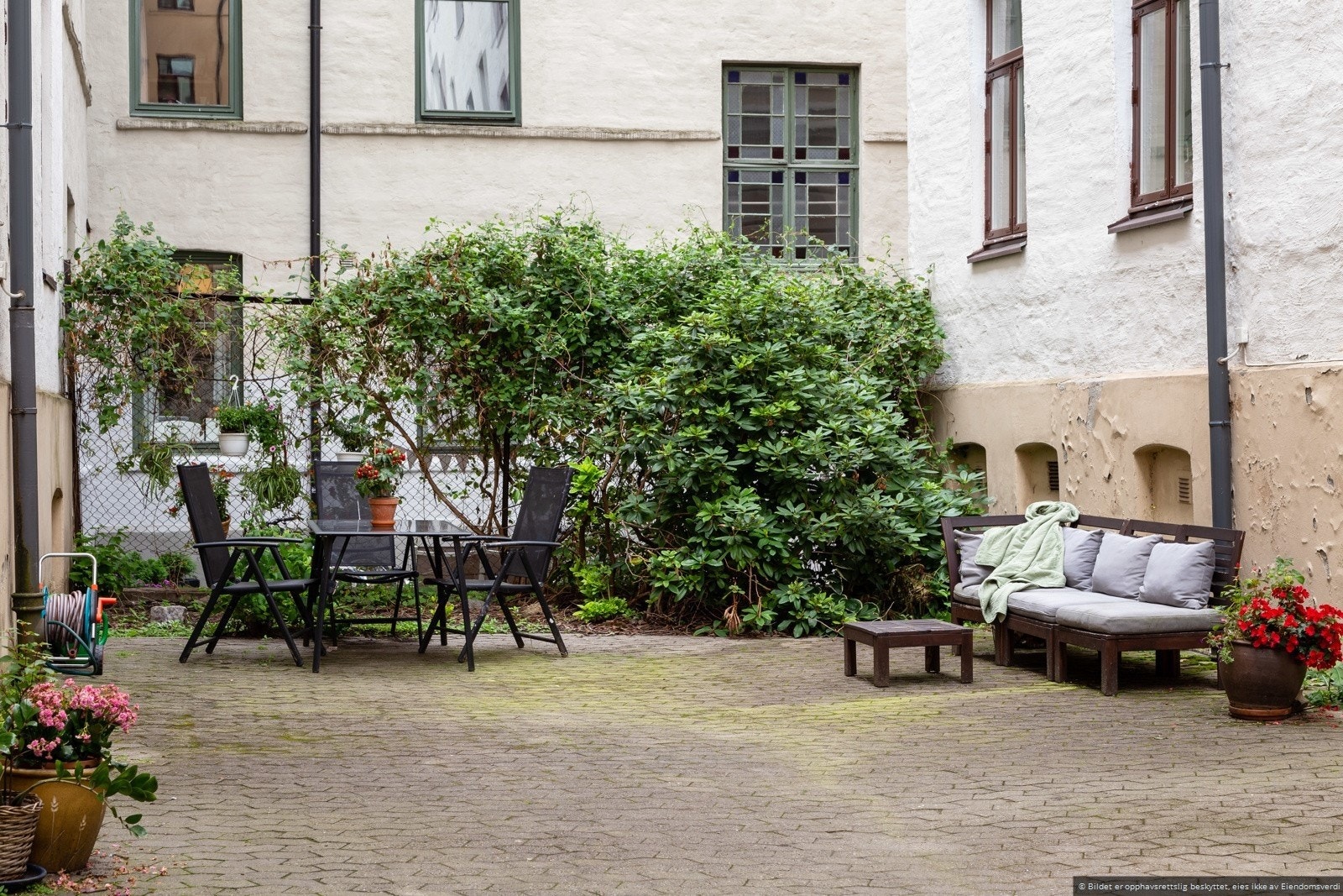 Koselig og lukket bakgård med spisebord og sittegruppe. Galleribilde