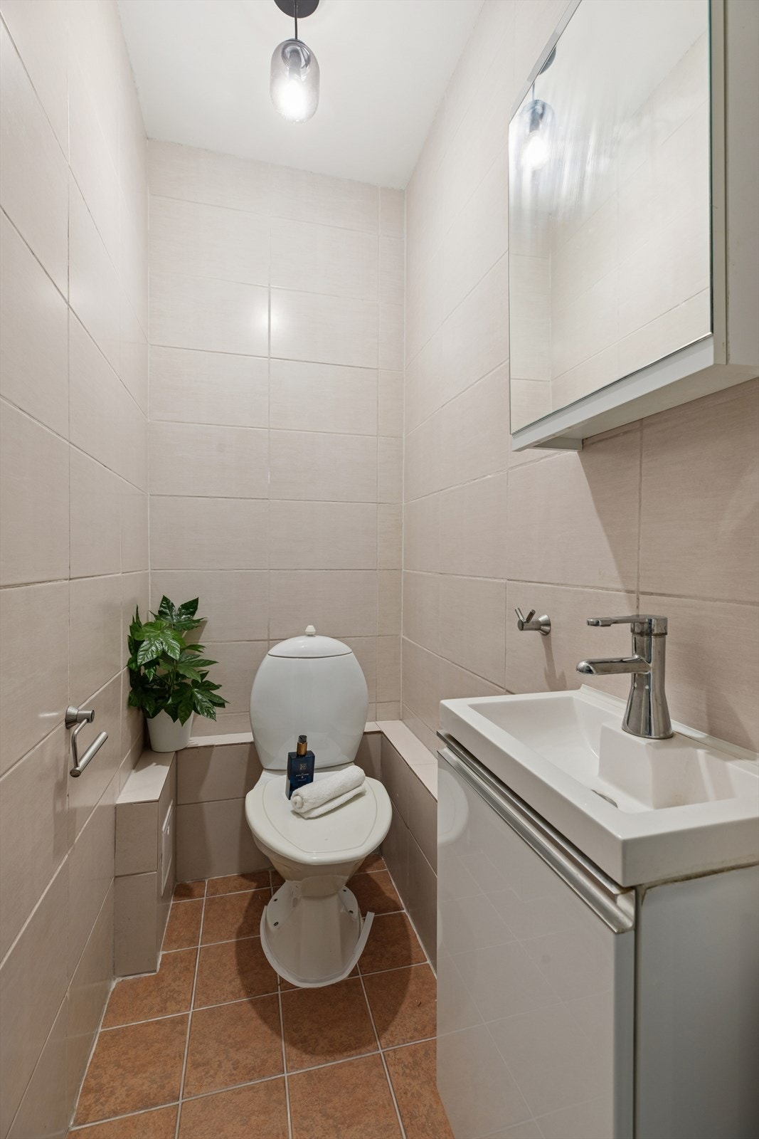 Toalettrommet har fliser på gulv og vegger, samt innredning med servant og toalett. Galleribilde