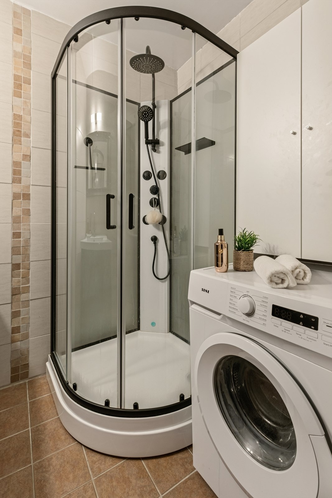 Dusjkabinett og opplegg for vaskemaskin gir praktisk funksjonalitet på badet. Galleribilde