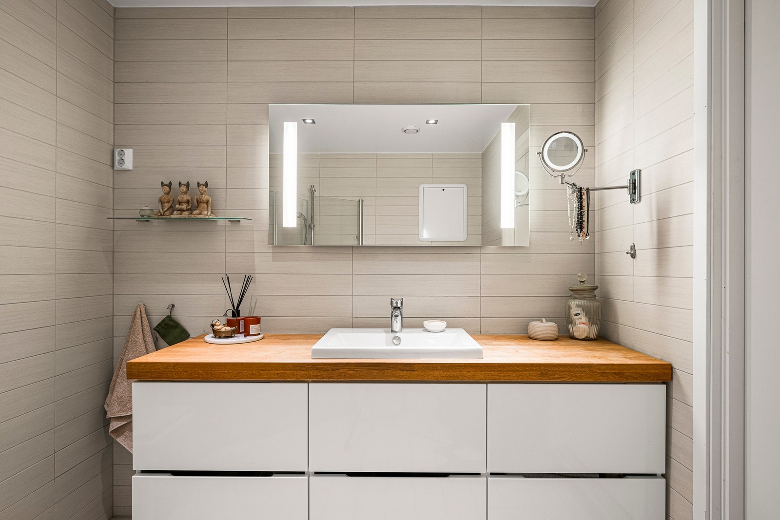 Badet inneholder vegghengt toalett, helstøpt servant, skuffer under servant med slette fronter og dusjdører i klart glass. Galleribilde