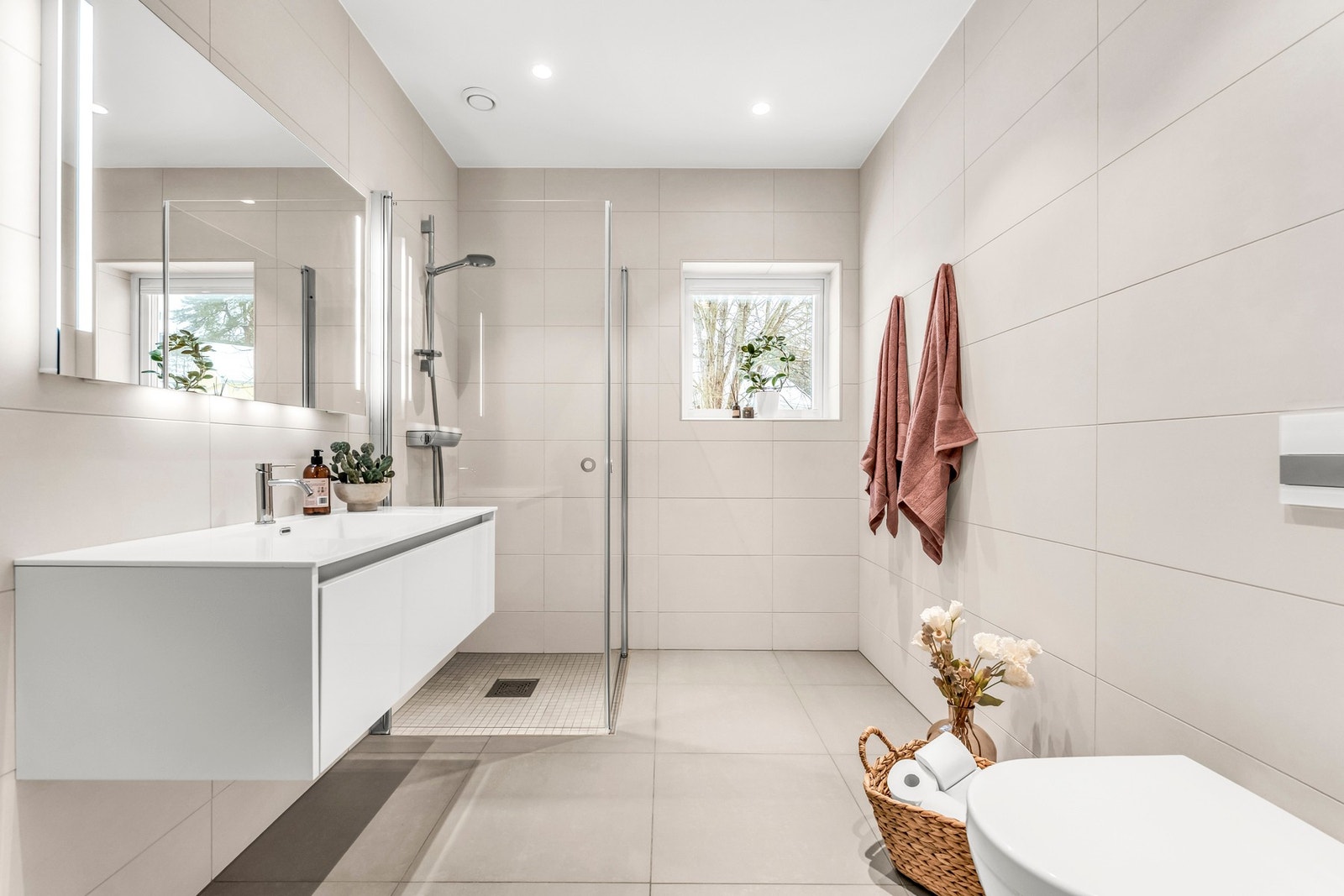 Lyst og pent bad med dusj, vegghengt toalett, stort speil og vindu som gir naturlig lys. Galleribilde