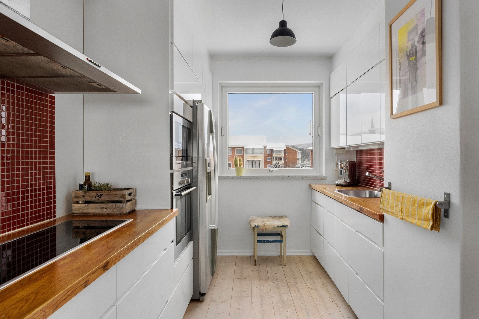 Kjøkkenet har innredning med glatte høyglansede fronter og benkeplaten er av heltre med enkel stålkum. Galleribilde