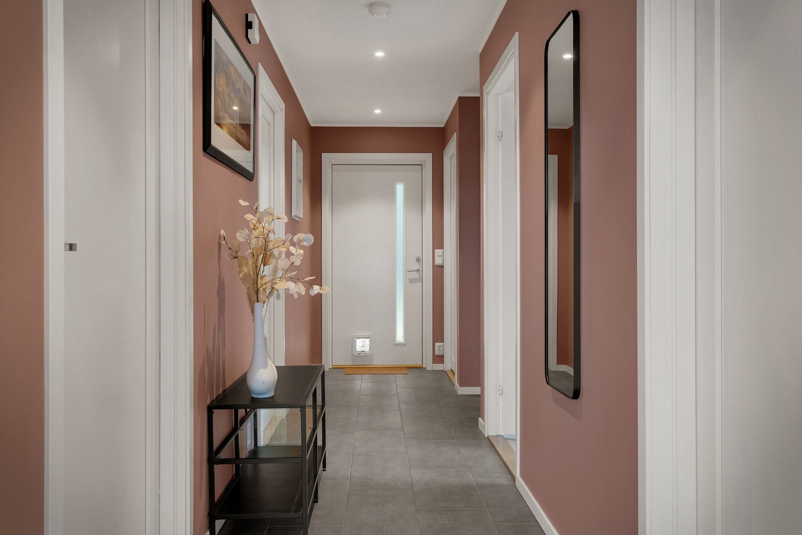 Man kommer videre inn i en romslig gang på ca. 9,4 kvm med flislagt gulv og lyse, malte gipsflater på vegger og tak Galleribilde