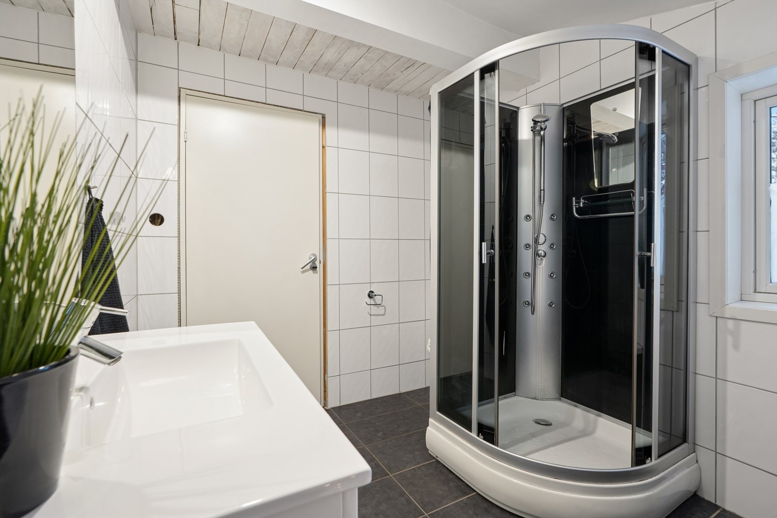 Videre er rommet utstyrt med dusjkabinett, vegghengt toalett og innmurt badekar. Galleribilde