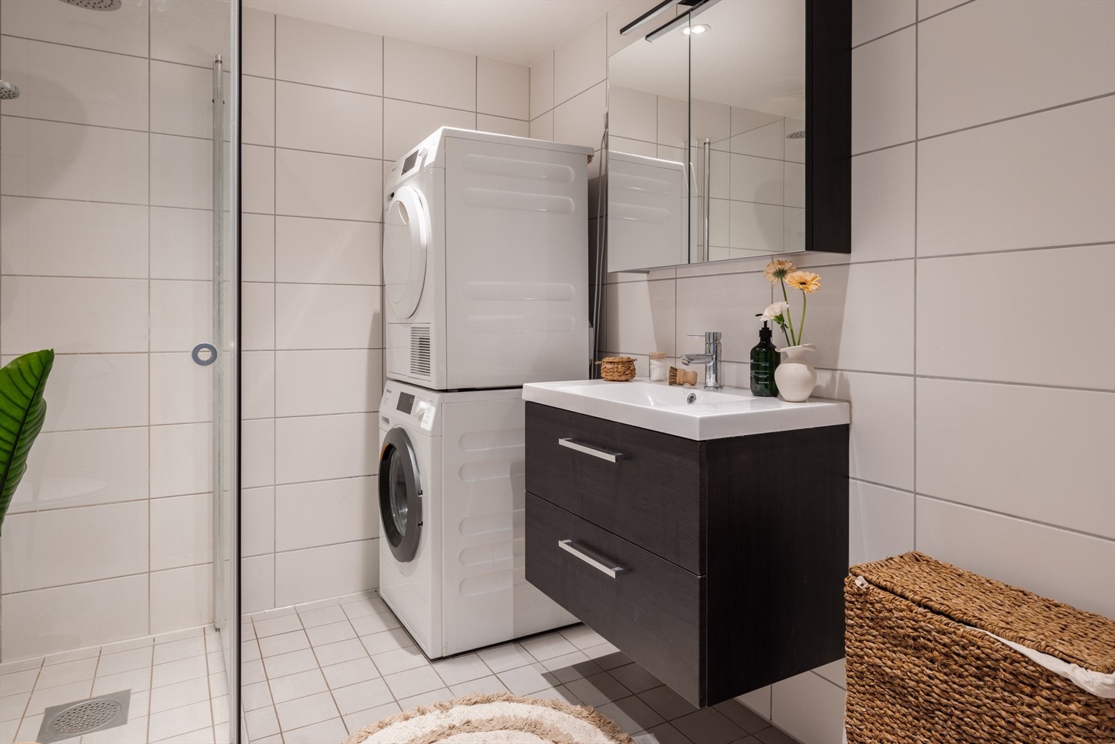 Den mørke, moderne baderomsinnredningen skaper en fin kontrast mot de lyse flisene. Galleribilde