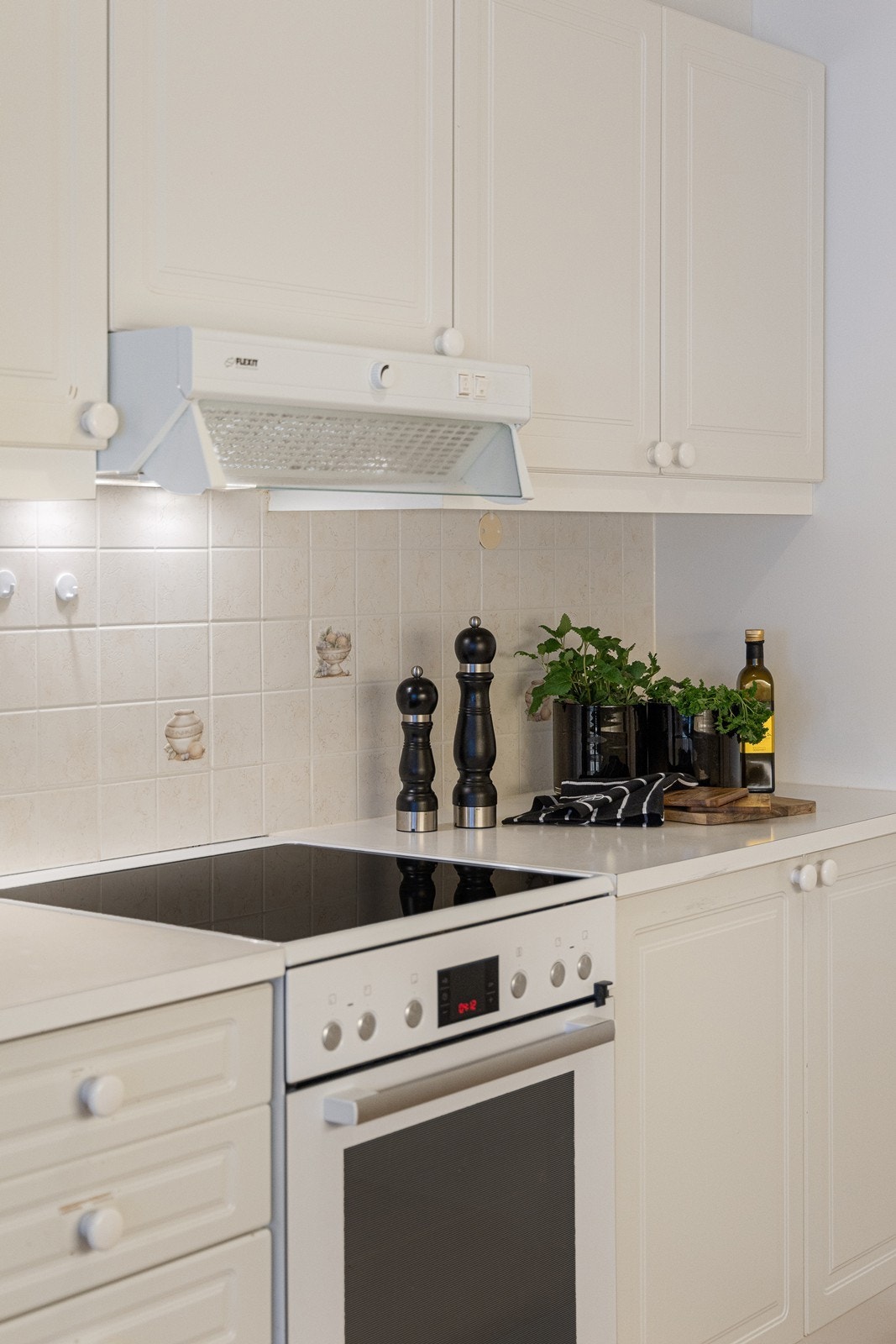 Innredningen har profilerte fronter og hvit laminatbenkeplate med nedfelt kum. Det er nisje for komfyr og opplegg for oppvaskmaskin. Galleribilde