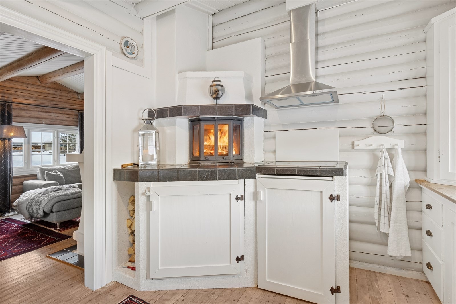 Plassbygd innredning, trebenkeplate og fliser ved peisen skaper et tidløst og stemningsfullt uttrykk. Galleribilde