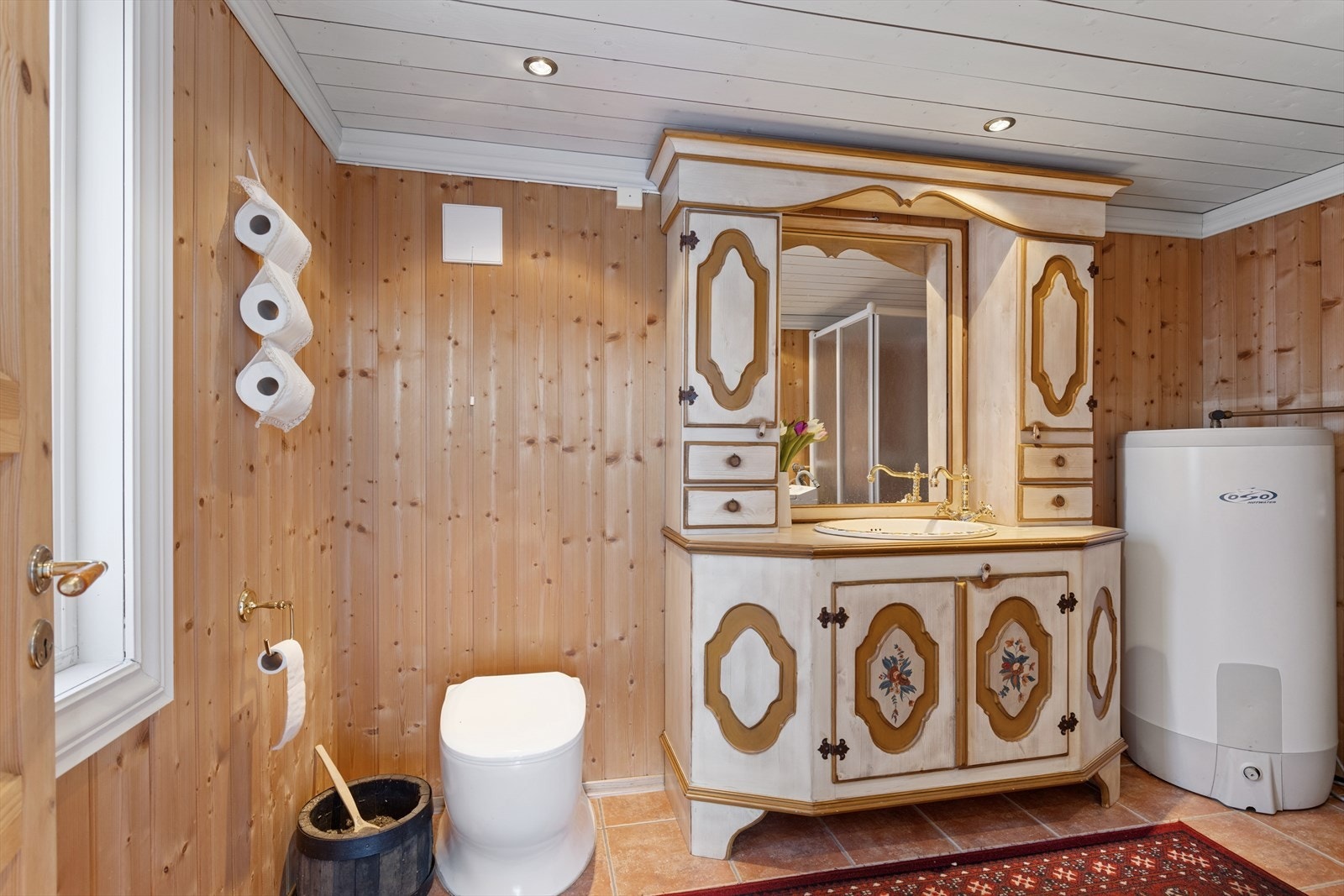 Badet i uthuset byr på en kombinasjon av tradisjonell hyttefølelse og moderne gulvvarme fra 2025. Galleribilde