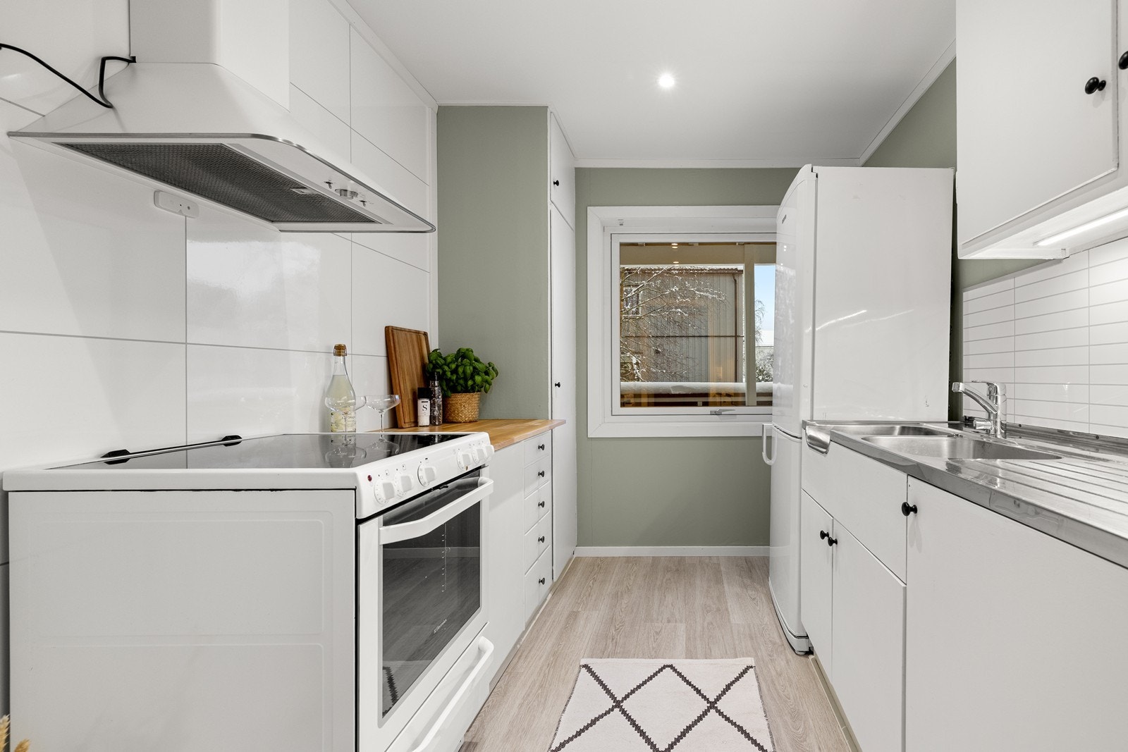 Innredningen har glatte, malte fronter og en benkeplate i tre med en nedfelt kum i rustfritt stål. Her er det plass til frittstående oppvaskmaskin, samt komfyr og kjøl-/fryseskap. Galleribilde