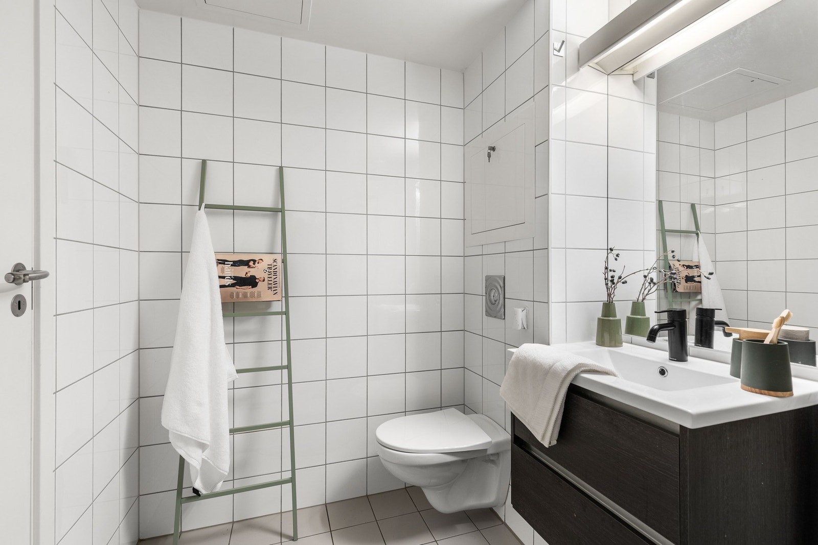 Baderomsinnredningen har mørkebrune skuffefronter, heldekkende servant samt speil med integrert belysning. Galleribilde