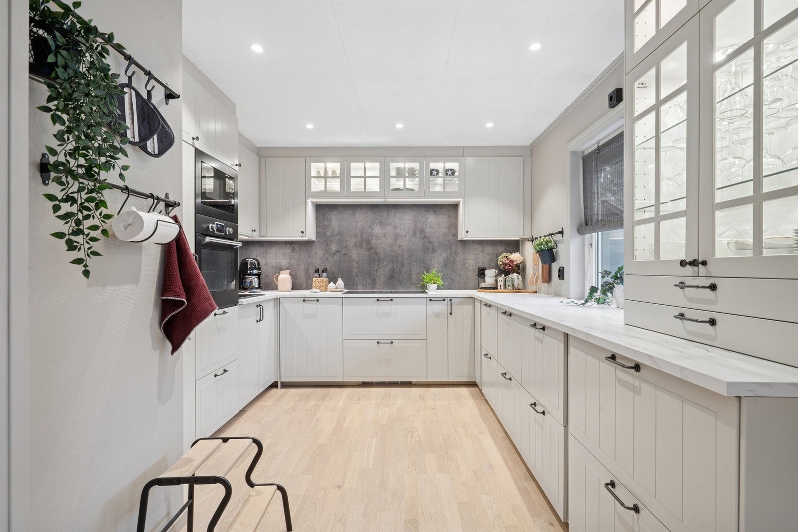 Ikea kjøkkeninnredning fra 2024 med profilerte fronter og integrerte hvitevarer. Overskap med belysning under. Enkelte vitrine overskap. Galleribilde