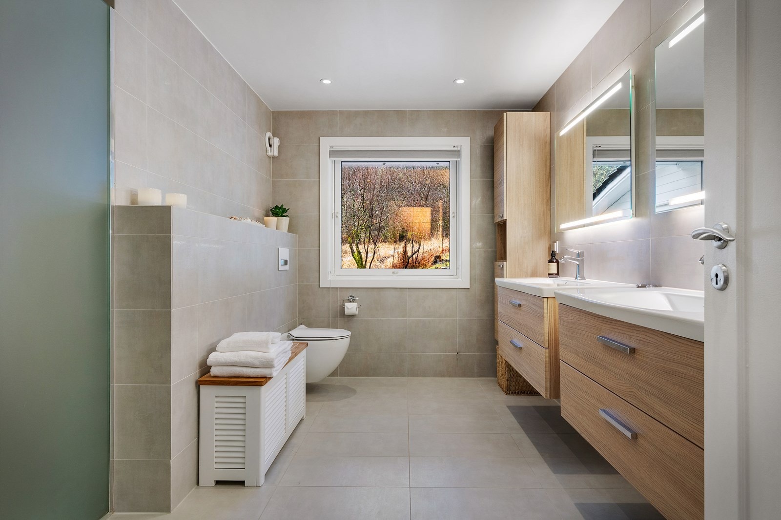 Badet er innredet med to servant, vegghengt toalett og dusjhjørne. Galleribilde