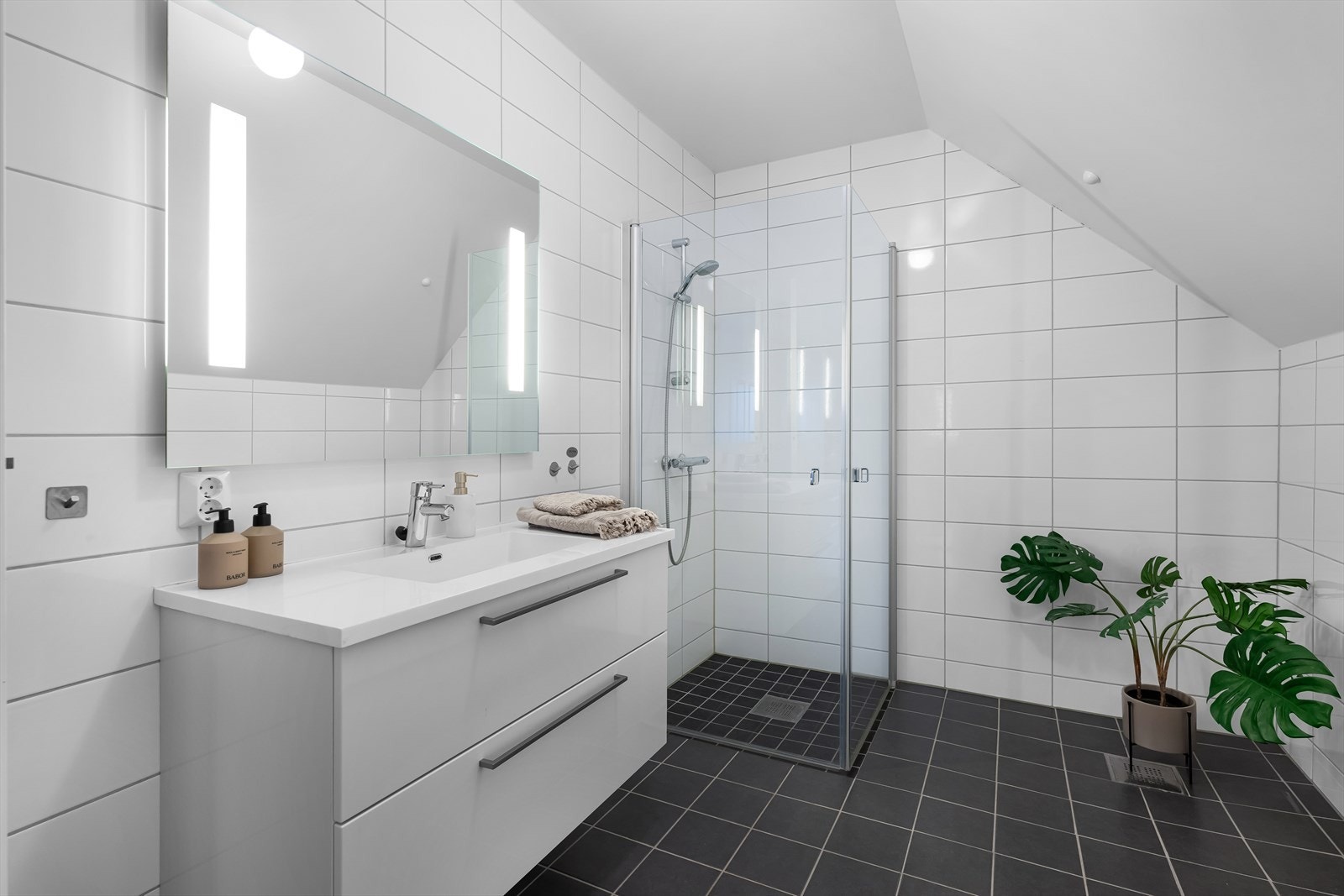 Lys og slett baderomsinnredning med skuffer og heldekkende servant. Galleribilde