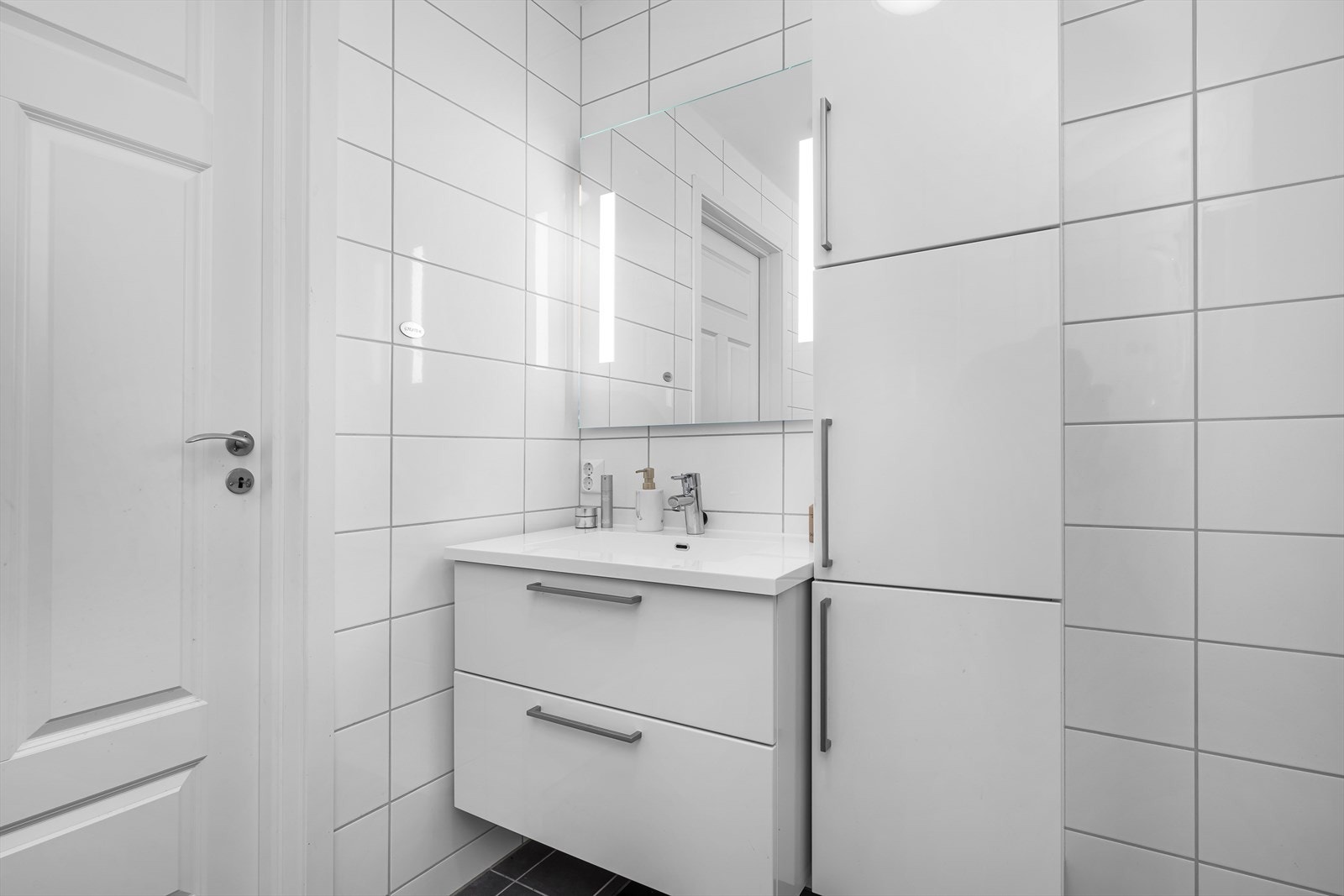 Baderomsinnredningen er er i lys utførelse med rikelig med både oppbevaringsplass i høyskapet og i skuffene under den heldekkende servanten. Galleribilde