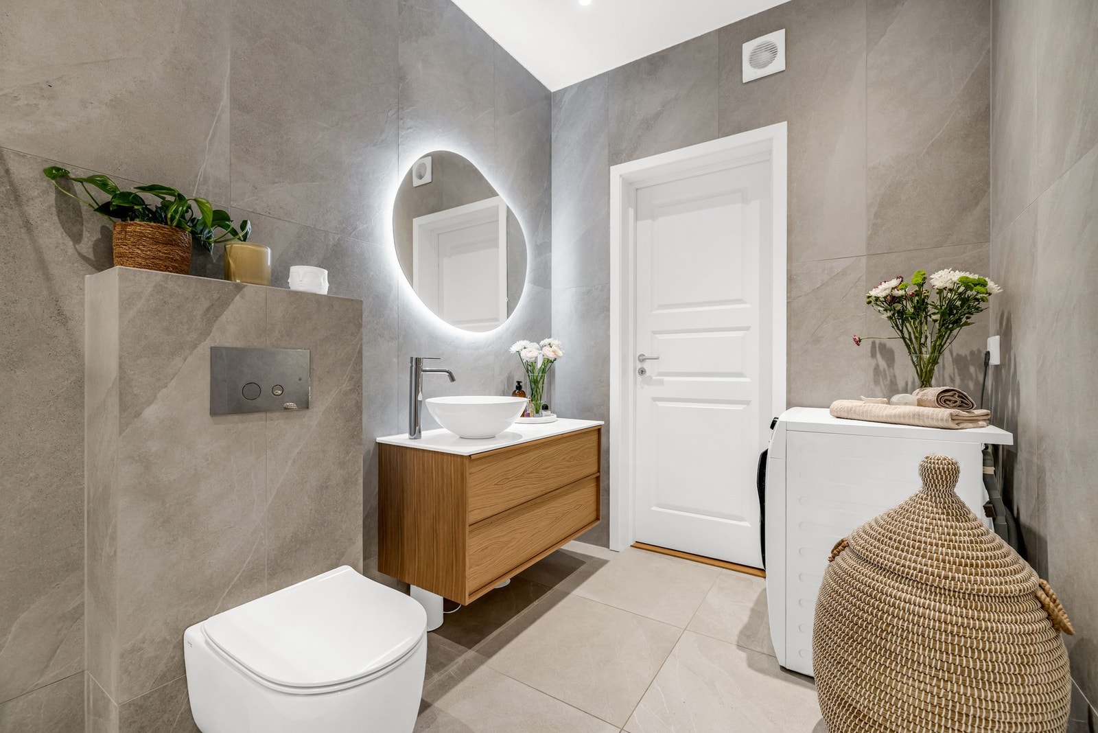 Rommet er innredet med servant, veggmontert toalett, dusjvegger/-hjørne og opplegg for vaskemaskin. Galleribilde