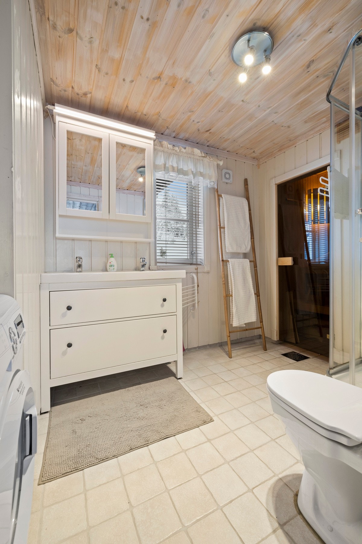 Badet er innredet med wc, dusjkabinett, dobbel servant integrert i skuffeinnredning, speilskap med lys og opplegg for vaskemaskin Galleribilde