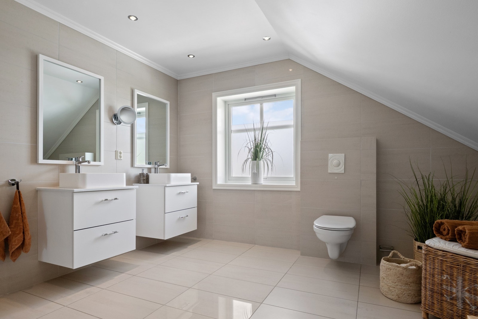 Badet i 2. etasje er romslig og stilrent, med store beige fliser på vegg og gulv. Galleribilde