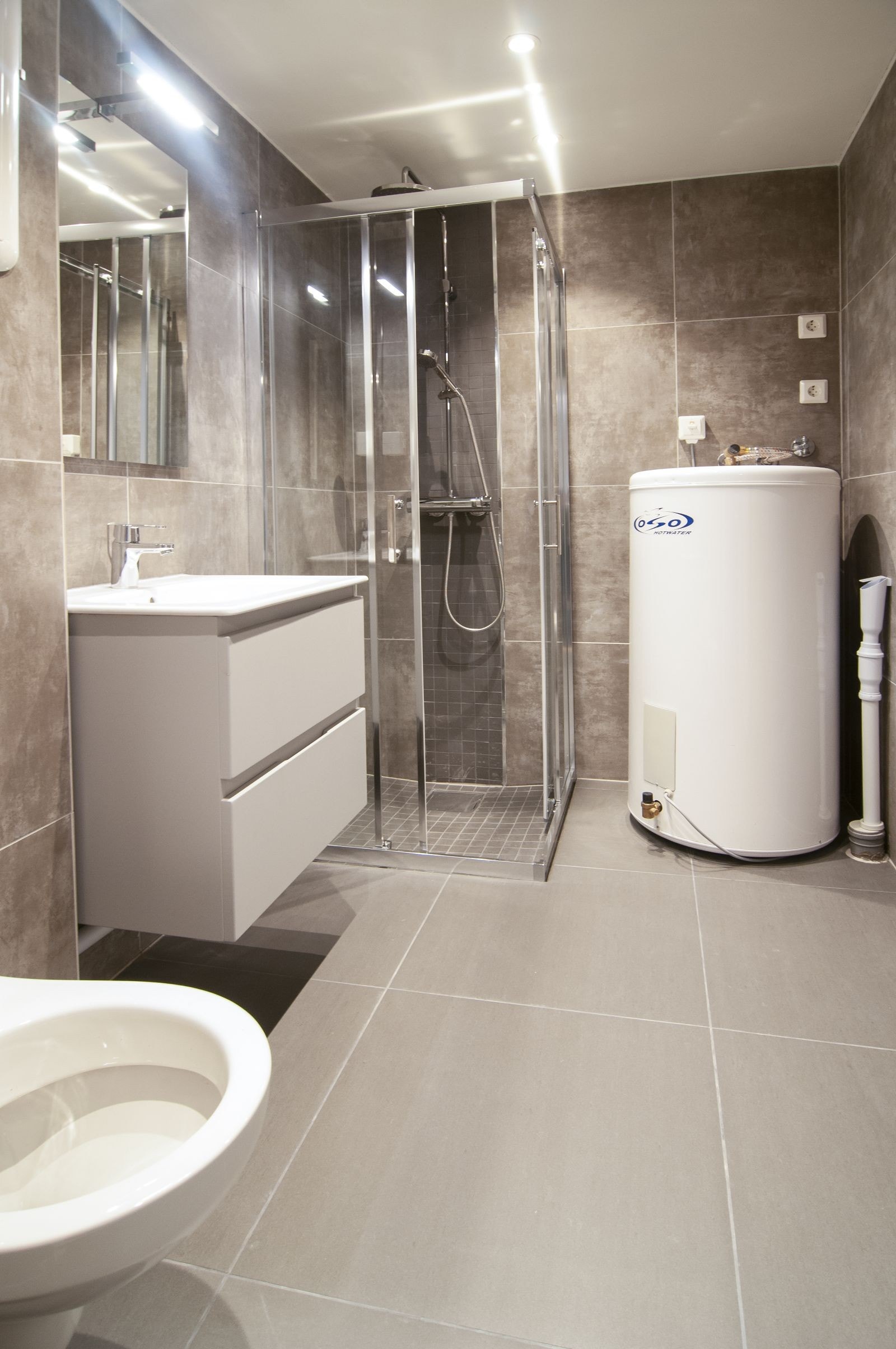 Lyst og lekkert bad med opplegg for vaskemaskin og tørketrommel. Galleribilde