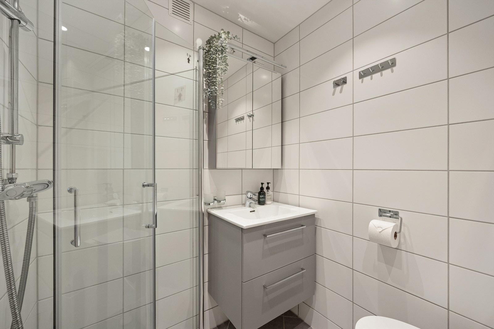 Her er det flislagt gulv med elektriske varmekabler og et praktisk dusjhjørne med svingdører. Galleribilde